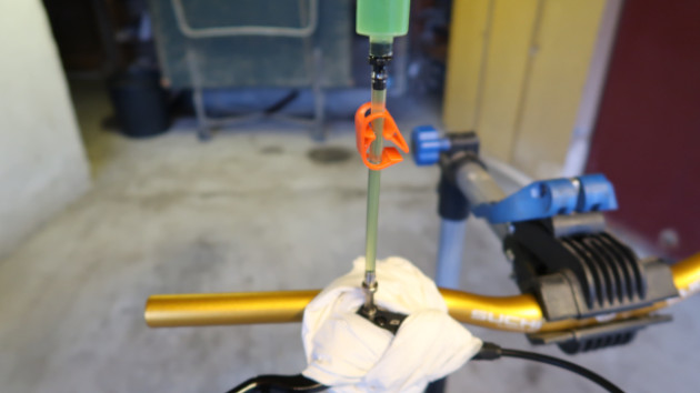 Le mécanicen repousse le piston de la seringue pour remplir le maître cylindre du frein hydraulique Clarks