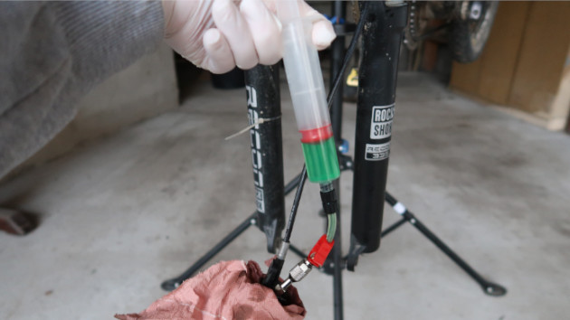 Mécanicien repoussant le piston la seringue n°2 pour renvoyer du liquide frein VTT